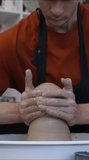 Close-up of a potter's hands making a ceramic jug on a potter's wheel. Vertical video. 