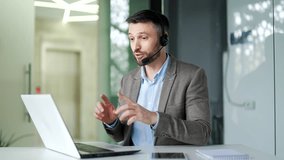 Businessman in wireless headset talking on a video call looking at camera sitting at the workplace in office. The manager has a business meeting, speaks remotely, communicates at an online conference - Powered by Shutterstock - Get 15% off with code: PIKWIZARD15