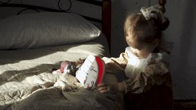 A little girl plays with cosmetics and a purse on the bed.
