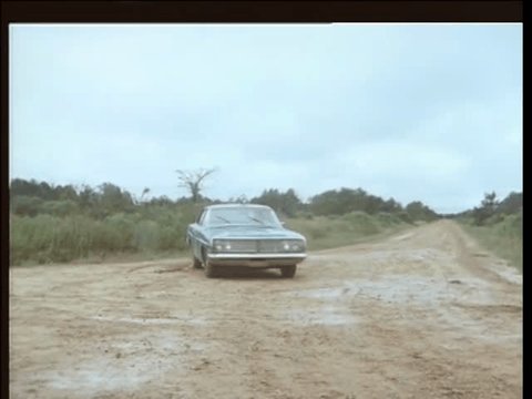 Police car stopping short on dirt road, 1970s. Redaksjonell arkivvideo