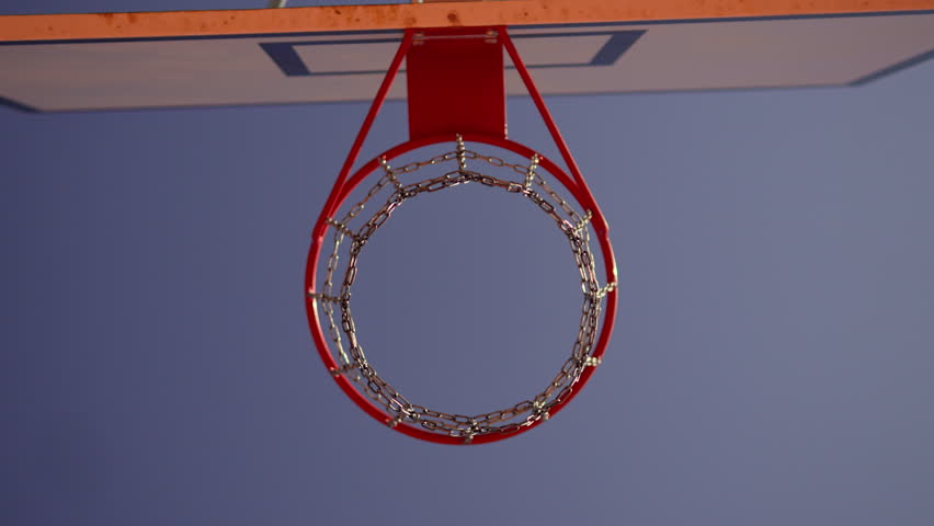Ball hits backboard of basketball hoop and bounces without hitting basket, low angle view. Bottom view of basketball basket with shiny chains against sky and miss in game outdoor.