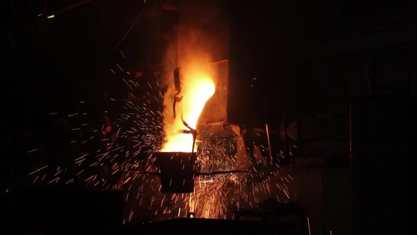 Industrial steel casting process at manufacturing plant shows molten metal pouring from ladle, foundry workers oversee precise metallurgical operations, sparks fly around in dark factory setting.