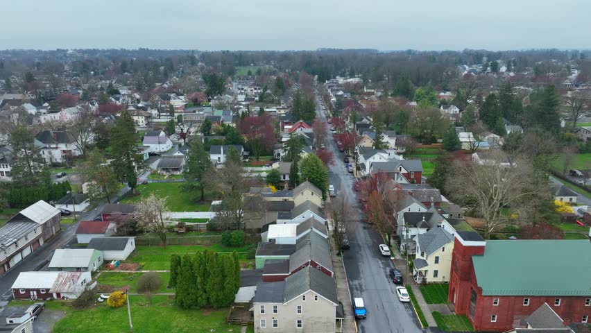 Rainy and clouds day in small american town with colorful trees and houses. Residential area with homes and garden in USA. Aerial lateral wide shot.