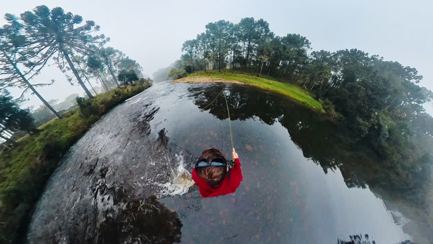 Fisherman crossing the rapid clean river in waders with fishing rod