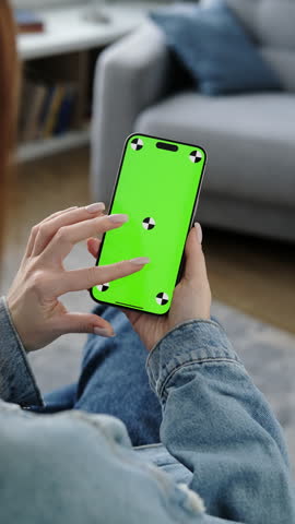 Woman using smartphone vertical green screen. Female holding in hand portable gadget. Tracking markers. Indoors. Browsing social network, news. Mock-up for tracking. Watching content. Vertical video
