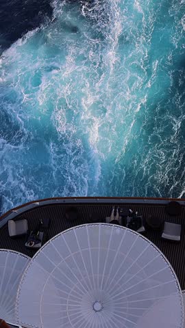 Top view of sea and waves of sailing ship. Lounge promenade deck on cruise liner. Taken from hand, Vertical video