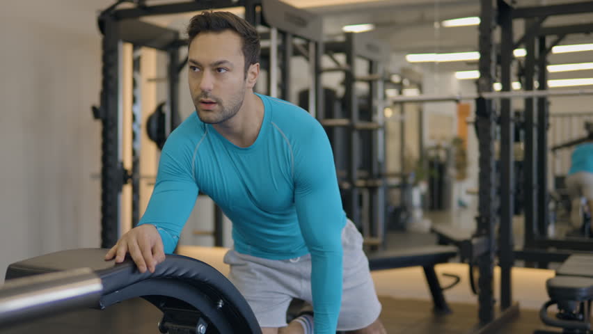A Single-Arm Dumbbell Row Exercise With A European Fit Man In A Workout Gym. Close-up Shot