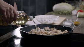 Cook pours sesame oil over chicken that has been fried in a pan, surrounded by other ingredients laid out on a table against a dark backdrop. Close up. Slow motion. 4k - Powered by Shutterstock - Get 15% off with code: PIKWIZARD15