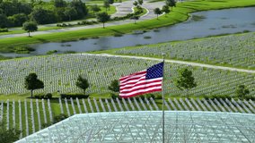 US national flag waving over military cemetery with rows of white tomb stones on green grass lawn. American Memorial Day concept - Powered by Shutterstock - Get 15% off with code: PIKWIZARD15