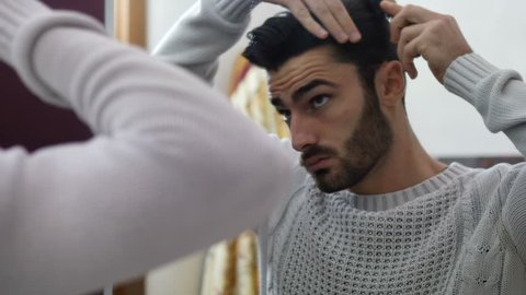 Handsome Young Man Brushing and Combing Hair in Mirror Getting Ready to Go Out