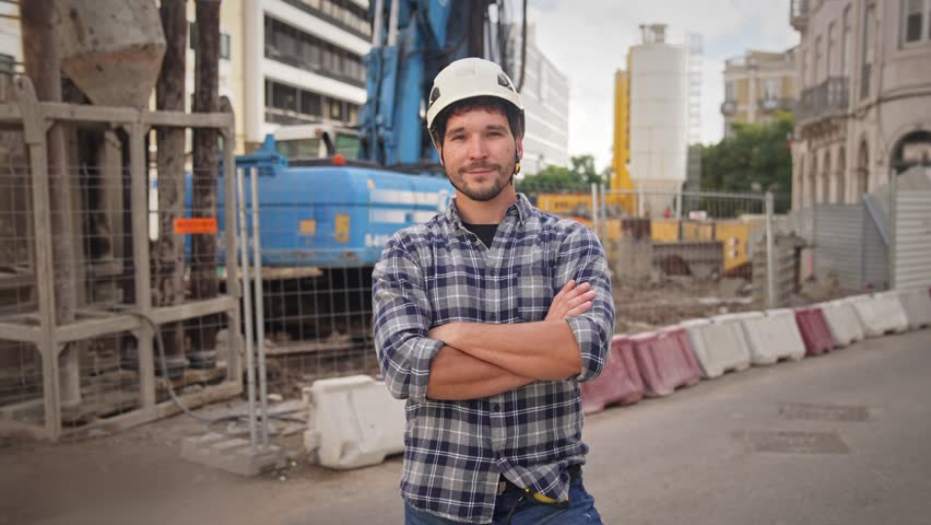 Confident construction site worker portrait. Smile constructor man look camera. Builder engineer wear white helmet. Real estate agent plaid shirt. Guy build new house city street. Erector person job.