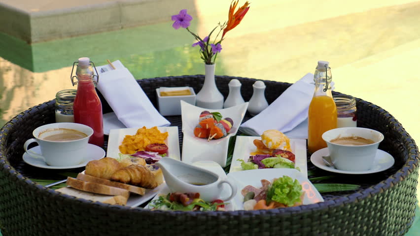 Sumptuous outdoor breakfast spread at luxury resort with variety of gourmet food and beverages, offering feast for senses against lush green backdrop. Gourmet travel and dining.