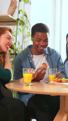 Portrait of multi-ethnic friends having a breakfast with orange juice and muffins at home