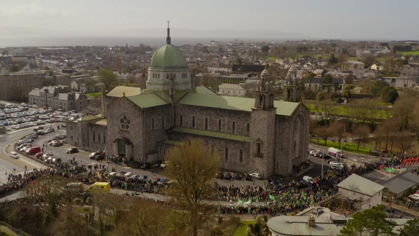 Panoramic aerial static establishing view of Galway Cathedral crowd gathered to watch parade on a sunny day