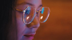 Close up female asian person working at a computer in colorful neon light. Freelancer wearing glasses reflecting screen of laptop. Designer drawing. Asian woman creating illustration. warm home light. - Powered by Shutterstock - Get 15% off with code: PIKWIZARD15