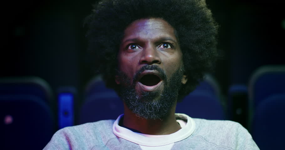 Close up of an awestruck man at the movie theatre.