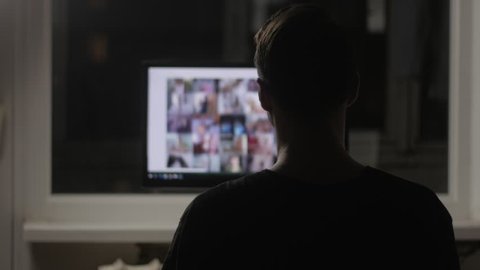 young man watching surfing pornography site on the web at night at home