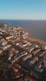sunset over streets of Spanish touristic city Salou, Catalonia, sea and coast with palm trees, luxury hotels and resorts, aerial drone view 4k, vertical video
