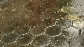 Heavy rain drops falling into puddles on textured floor