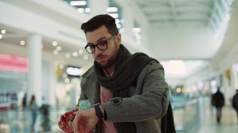 Close up of an attractive man wear coat with Christmas presents in a hurry at a mall smiling looking at a clock christmas family christmas decorations design tree love portrait slow motion