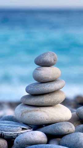Zen meditation background - balanced stones stack cairn close up on sea beach