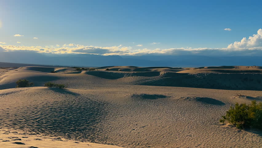 Sunset over Mesquite Flat Sand Dunes, Sun descends over the Mesquite Flat Sand Dunes, casting long shadows on the textured sands of Death Valley.