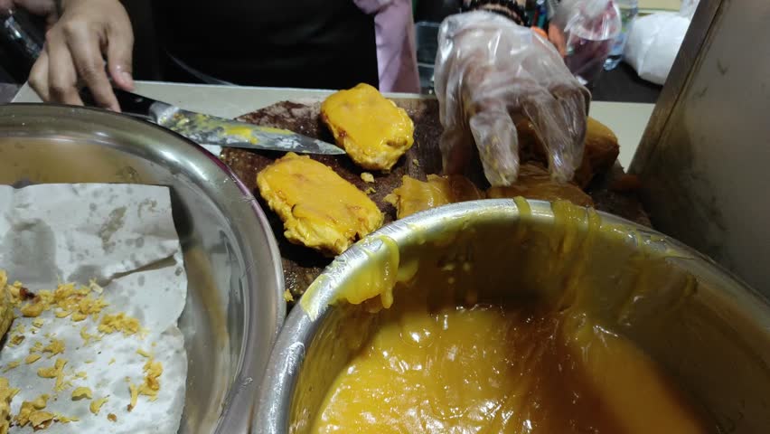 Hands are cutting the fried banana and smearing the Kaya jam on it