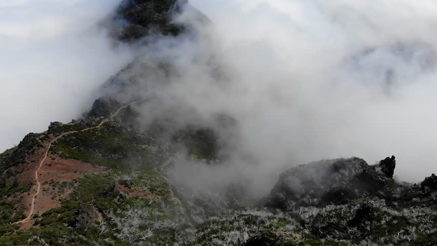 The drone captures the stunning landscape of Pico Ruivo on Madeira, showcasing rugged mountains, lush greenery, and winding trails that lead to breathtaking panoramic views.