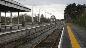 Deserted train station with multiple tracks and a signal tower, set against a backdrop of trees and overcast skies. Quiet transit setting, perfect for conveying solitude and transportation - Powered by Shutterstock - Get 15% off with code: PIKWIZARD15