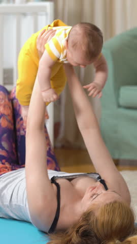 Young fit mother doing fitness exercises together with her baby in the nursery. A set of exercises for a young mother in the postpartum. Sport, motherhood, postpartum and active lifestyle. Royalty-Free Stock Footage #3479399549