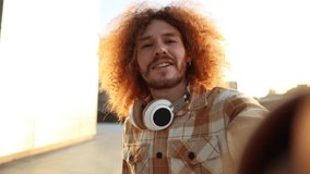 red-haired man records himself with his phone running looking at the camera - video call, live video social networks