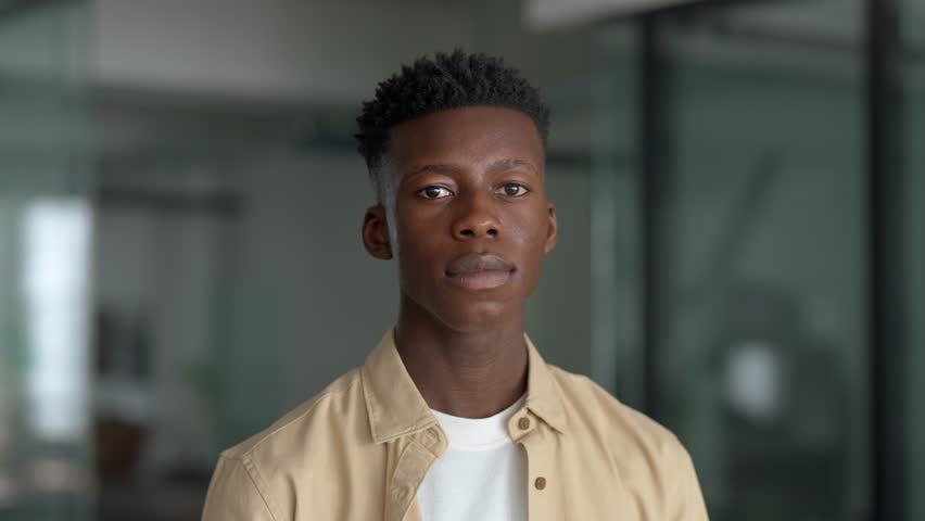 Close up portrait of young adult confident happy Black man student or company employee, smiling African guy professional entrepreneur, office worker standing indoors looking at camera. Royalty-Free Stock Footage #3479698527