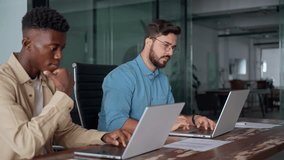 Two busy diverse business men company employees using laptops working in office. Professional young businessmen colleagues workers typing on computer technology at office workplace desk. - Powered by Shutterstock - Get 15% off with code: PIKWIZARD15