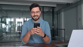 Busy happy young latin business man holding smartphone standing in office. Professional hispanic businessman entrepreneur or manager using financial banking apps on cell phone technology at work. - Powered by Shutterstock - Get 15% off with code: PIKWIZARD15