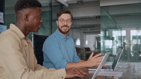 Two busy diverse male employees using laptops computers talking in office. Professional young business men workers team having conversation working on project sharing ideas sitting at work desk. - Powered by Shutterstock - Get 15% off with code: PIKWIZARD15