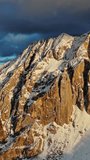 Aerial view of amazing rocky mountains in snow at sunset, Dolomites, Italy. Vertical video