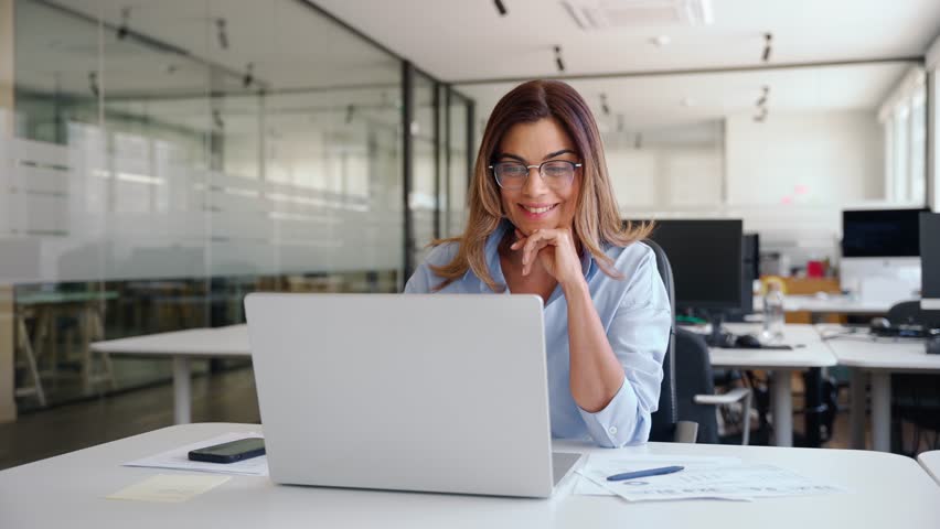 Happy busy mature business woman employee in office using laptop at work, smiling professional middle aged female company manager working looking at computer at workplace.