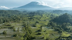 Aerial time lapse video of rice field landscape at golden hour with view of Mount Agung, at Sidemen, Bali