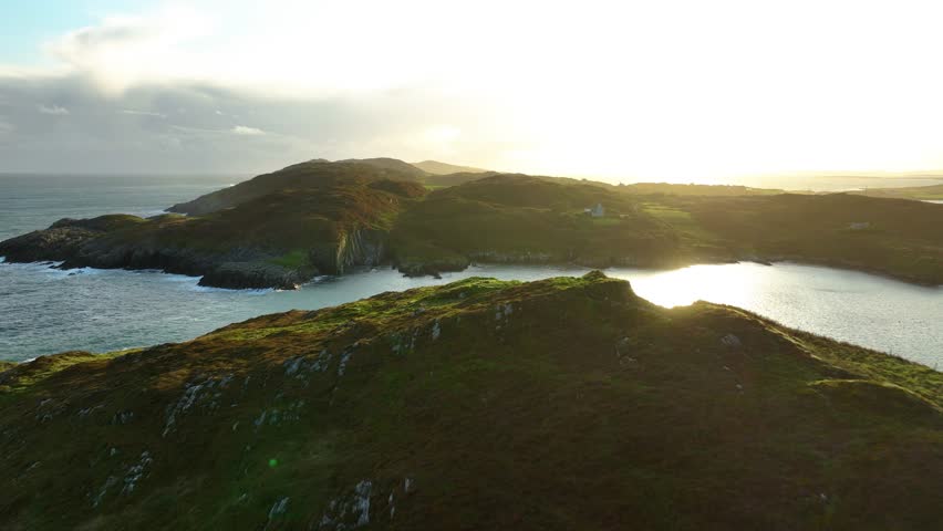Picturesque lighthouse with white house on rocky island landscape at sunset