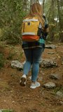 Vertical video. A female tourist with a backpack hikes through the forest and discovers ancient tombs, she peers inside.