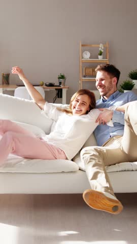 Couple Running To Sofa And Jumping At Home
