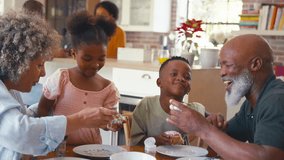 Grandparents with grandchildren indoors at home decorating cupcakes with icing and sprinkles together with parents in background - shot in slow motion - Powered by Shutterstock - Get 15% off with code: PIKWIZARD15