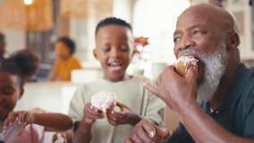 Grandparents with grandchildren indoors at home decorating cupcakes with icing and sprinkles together with parents in background - shot in slow motion - Powered by Shutterstock - Get 15% off with code: PIKWIZARD15