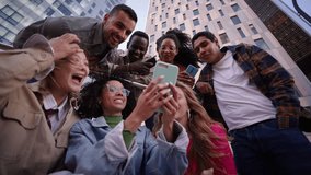 Group of young people watching something at phone sitting on stairs. Smiling multicultural friends looking social media outside the university campus. Students in their free time. - Powered by Shutterstock - Get 15% off with code: PIKWIZARD15
