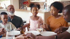 Multi-generation family at home closing eyes and saying prayer before eating meal together - shot in slow motion - Powered by Shutterstock - Get 15% off with code: PIKWIZARD15
