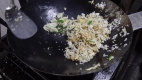 Cooking traditional Indonesian fried rice using a big wok shot with handheld movement.