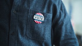 Close up of anonymous African American man or US citizen putting on badge with USA flag logo and inscription I Voted. Male voter at polling station after voting. Election Day in the United States. - Powered by Shutterstock - Get 15% off with code: PIKWIZARD15