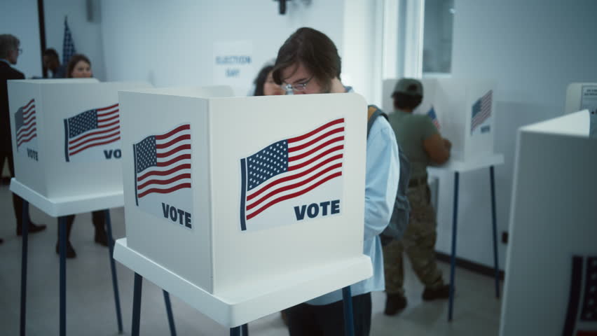 Asian woman comes to vote in booth in polling station office. National Election Day in the United States. Political races of US presidential candidates. Concept of civic duty. Slow motion. Dolly shot.
