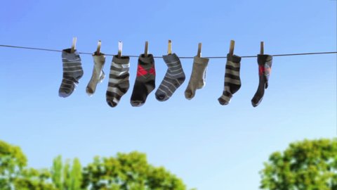 Laundry Line with Baby Socks in the Wind (HD)
Baby boy sock hanging on laundry line to dry in the wind and sun.
