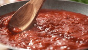 Mixing Tomato Sauce for Spaghetti Bolognese or Pizza with a Wooden Spoon in the Pan - the Hot Dish Bubbles and Steams in Slow Motion - Powered by Shutterstock - Get 15% off with code: PIKWIZARD15
